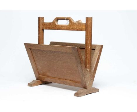 A ROBERT THOMPSON OAK MAGAZINE RACK with panelled sides and loop handle, on octagonal supports and trestle base, carved mouse