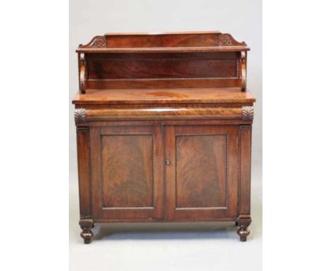 A VICTORIAN MAHOGANY CHIFFONIER, the panelled back with scroll carved surmount and shelf on scroll supports, leaf carved cush