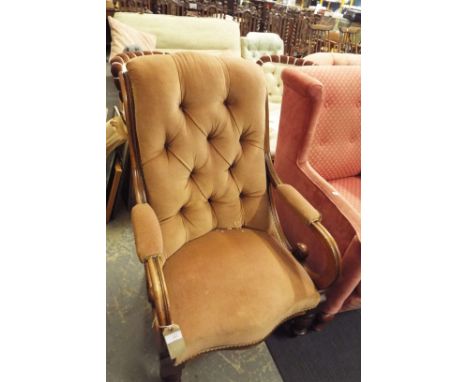 A mahogany framed armchair having scrolled arms and button-back upholstery resting on turned supports