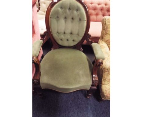 A Victorian walnut framed button-back elbow chair having scrolled arms resting on turned front supports 