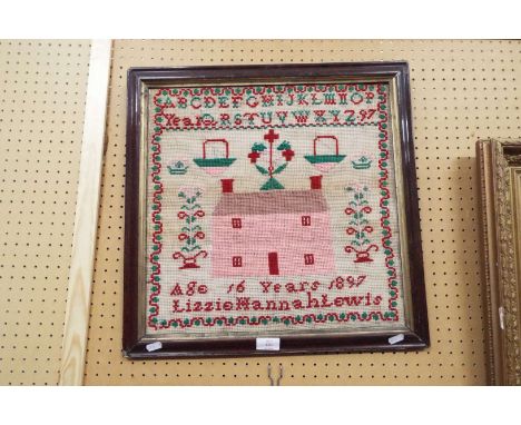 A Victorian woollen tapestry sampler by Lizzie Hannah Lewis, aged 16, featuring a central house, dated 1897 in ebonised frame