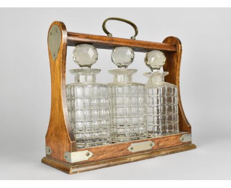 An Edwardian Oak Three Bottle Tantalus, Locked and Missing Key, 32.5cms Wide 