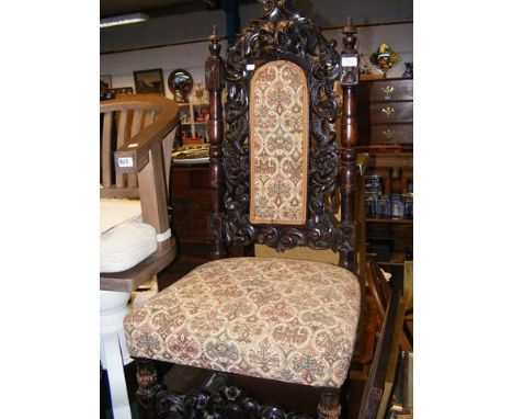 An antique carved high back hall chair with tapestry back panel and seat 