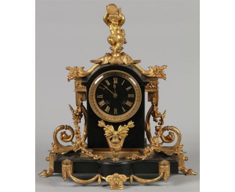 A black marble mantel clock with gilded ornaments and a fire-gilt puto. France, late 19th century.H.: 40 cm.