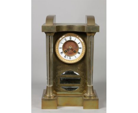 A brass mantel clock with glass columns. Early 20th century.H.: 35 x B.: 22 cm.
