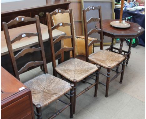 A set of three oak ladder back bedroom chairs together with an elbow chair, octagonal topped occasional table and table lamp