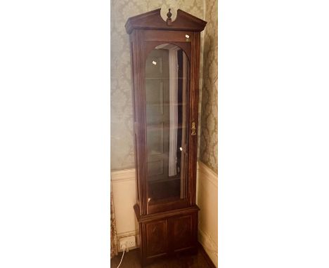 A 20th Century oak display cabinet in a longcase manner, broken pediment centred with a turned finial, above an arched glazed