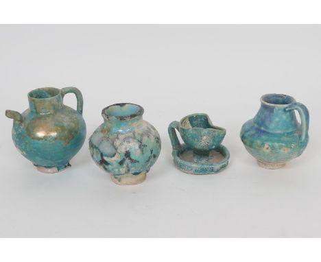 Four examples of ancient Persian faience pottery (12th/13th Century) comprising a small baluster oil jug with copper splashed