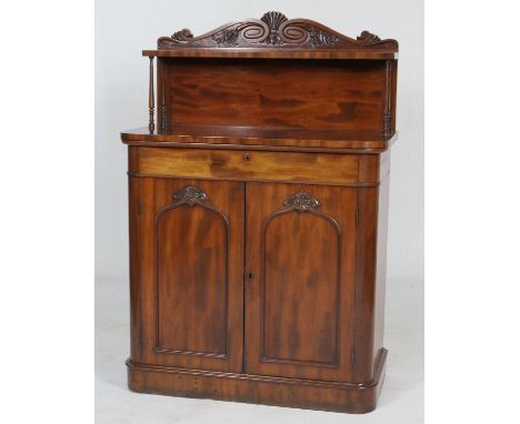 Early Victorian mahogany chiffonier, the back panel carved with a shell and paper scrolls, fitted with a single shelf with fi