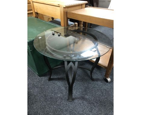 A circular wrought iron glass topped lamp table