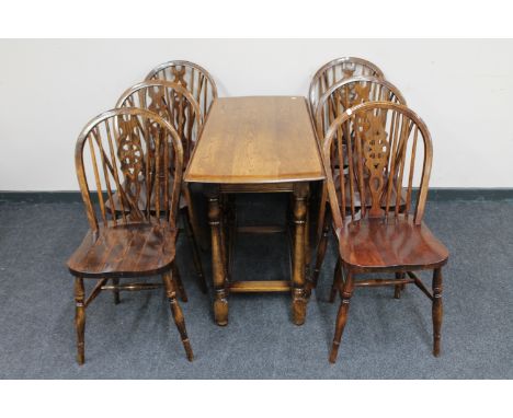 A 20th century oak gate leg table with a set of six wheel back chairs 