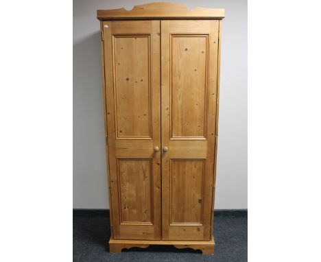 A pine double door hanging wardrobe fitted a shelf 