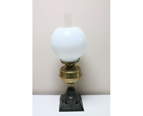 An antique brass oil lamp with glass chimney and shade on cast iron base 