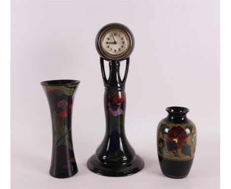 A glossy earthenware mantel clock, South Holland, ca. 1930. Polychrome floral decoration, h 33 cm. Comes with two glossy eart