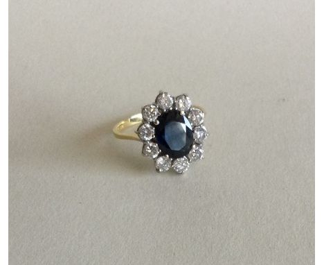 A large oval diamond and sapphire circular cluster ring in 18 carat and platinum claw mount. Approx. 4 grams. Est. £500 - £80