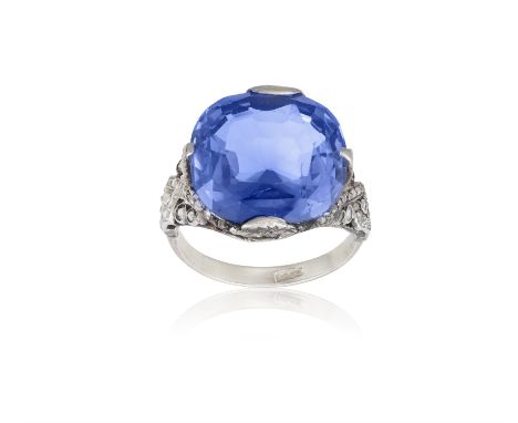 A Synthetic sapphire and diamond ringThe cushion-cut synthetic sapphire, claw-set between trifurcated shoulders, highlighted 