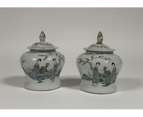 A pair of Chinese famille rose porcelain baluster jars and covers, c. 1900, each painted to the front with ladies in a garden