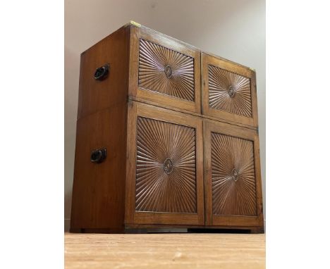 An Anglo-Indian teak two-part campaign cabinet, mid 19th century, the brass-bound top above two doors with brass rule edge an