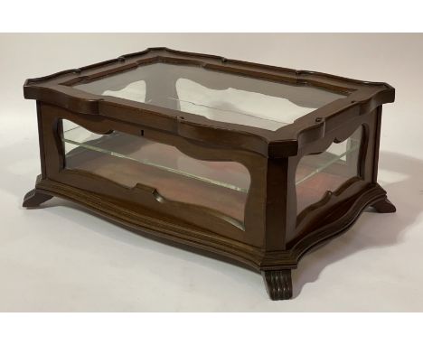 A late Victorian mahogany table-top display case of serpentine outline, the glazed hinged lid and case enclosing a shelf to i