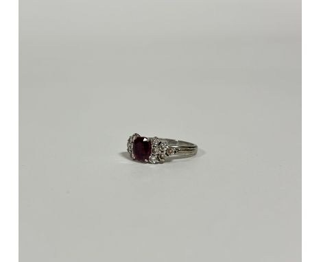 A ruby and diamond cluster ring, the oval-cut ruby weighing c. 1ct, (ruby chipped and with scratches) claw-set between twin g