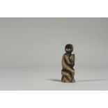 A Japanese carved bone netsuke, 19th century, modelled as a monkey holding a giant chestnut.