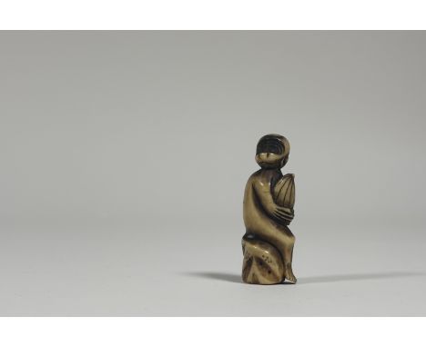 A Japanese carved bone netsuke, 19th century, modelled as a monkey holding a giant chestnut. Height 5.75cm