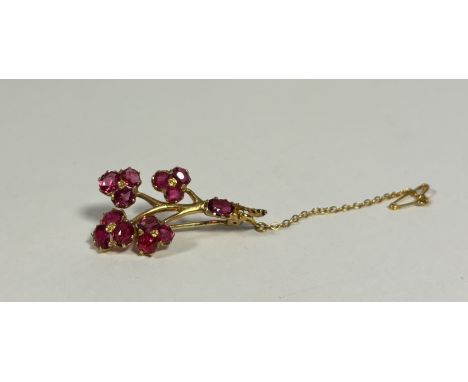 A ruby-set brooch, formed as a flowering branch, set with four three-stone flowerheads, claw-set, the branch claw-set with a 