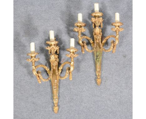 A pair of Louis XV style gilt metal three-light sconces, 20th Century, flaming swagged urn finials, the branches embellished 