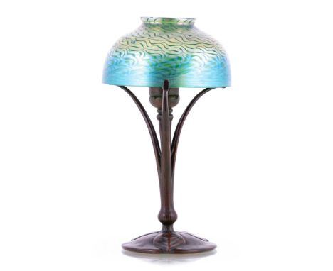 Tiffany Studios, a Favrile glass and patinated bronze table lamp, circa 1910, the base cast with three branched shade support