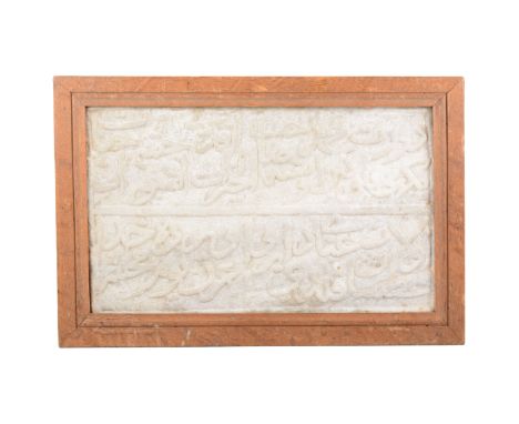 An Islamic carved stone panel, carved with two lines of Quranic inscription,  mounted in a 19th century oak frame, panel 22cm