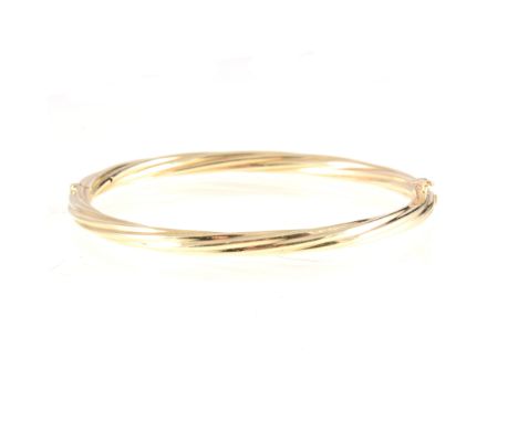 A 9 carat yellow gold modern half hinged bangle, 4.5mm wide hollow polished twisted design, hallmarked London (imported) 1983