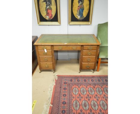 An early 20th Century oak desk, with inset tooled green leather writing surface, above a single frieze drawer, flanked by two