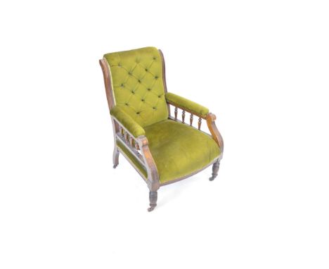 A Victorian oak easy armchair upholstered in bottle green velour, with scroll-over back and channelled uprights enclosing a d