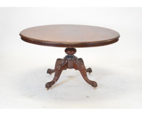 A Victorian mahogany breakfast table, with oval top above a central turned column, raised on a quadripartite base and ceramic