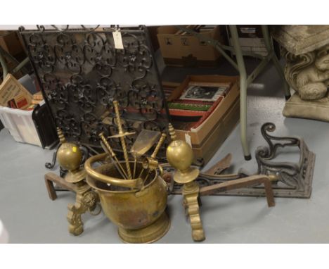 An early 20th Century cast iron fire fender; a set of large brass andirons; and fire tools in a coal bucket.