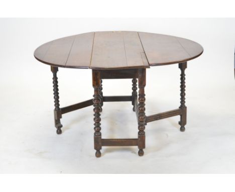 A 19th Century oak drop leaf table, with shaped top and two drop leaves, raised on bobbin turned legs united by a stretcher, 