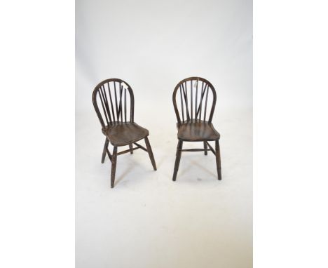 A pair of 20th Century elm spindle back chairs, with hooped backs and solid seats, raised on turned tapering legs united by s