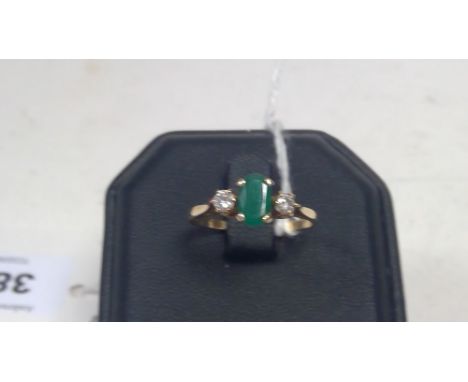 An emerald and diamond ring, the oval facet cut emerald flanked by two brilliant cut diamonds, on 9ct gold shank, ring size R