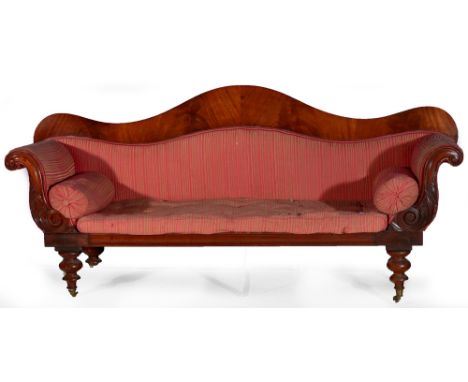 A Victorian mahogany framed sofa, the serpentine mahogany back with scroll-over and carved arms enclosing a red padded back, 