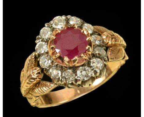 A Ruby and Diamond Cluster Ring claw-set round ruby within a frame of twelve old-cut diamonds between foliate shoulders, ring