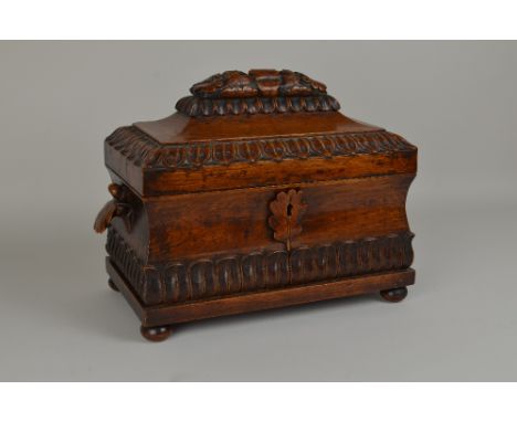 A 19th Century carved golden oak Tea Caddy of sarcophagus outline with acorn and leafage decoration, the interior with a pair