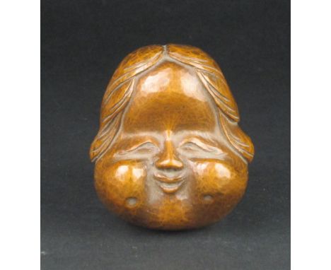 A Japanese wood Netsuke of an Okame Mask, late Meiji Period or later,Typically depicted with chubby features and smiling mout