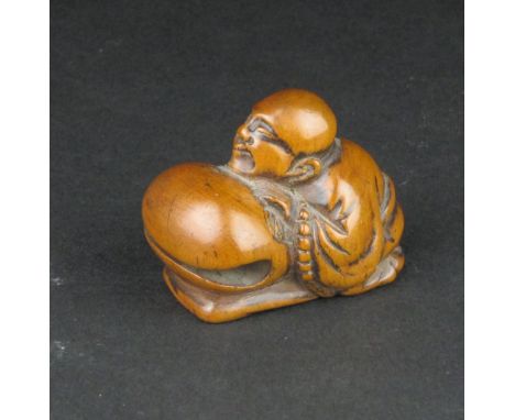 A Japanese wood Netsuke of a Monk, late Edo Period, kneeling beside a large mokugyo (temple bell), 1 1/2 in