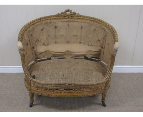 A 19th Century French carved giltwood Salon Sofa with floral and sheath surmount, in need of reupholstery, 3ft 6in W x 3ft H