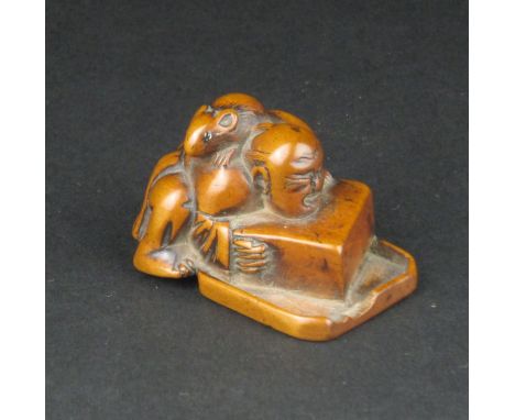 A Japanese wood Netsuke of a disappointed Rat Catcher, late Edo Period, The man crouched over an inverted box and tray, the r