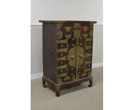 An antique Eastern elm Cabinet fitted two short drawers above a pair of brass bound doors enclosing numerous drawers etc on s