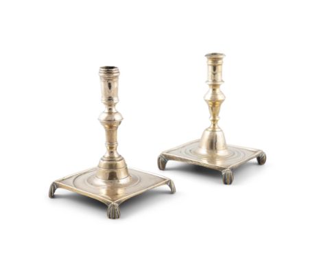 A PAIR OF 17TH CENTURY BRASS DESK CANDLESTICKS,each with turned knopped stems, raised on square platform bases and four short