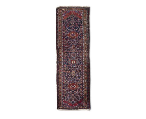 A LONG NORTH WEST PERSIAN WOOL RUNNER. 314 X 100CMwoven in red, blue and cream tones, with three medallions, against a ground