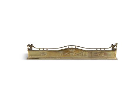 A BRASS FENDER EARLY 20TH CENTURY of neo-classical style, the pierced serpentine top rail above paterae and ribbons, 27cm hig