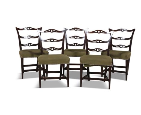 A SET OF FIVE MAHOGANY FRAMED DINING CHAIRS IN THE CHIPPENDALE STYLE the pierced carved ladder backs, the seats upholstered i